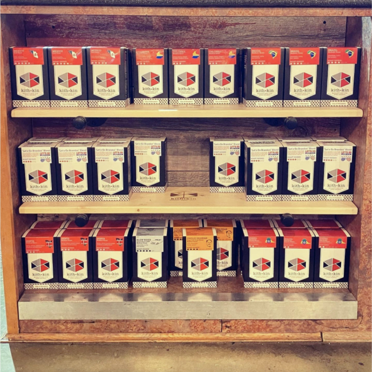 Three shelves filled with black and red boxes of Kith & Kin Coffee Roasters coffee.